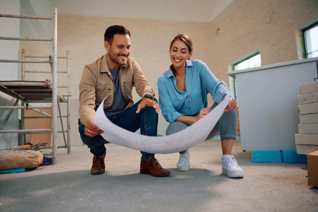 Happy couple analyzing blueprints during home renovation process.