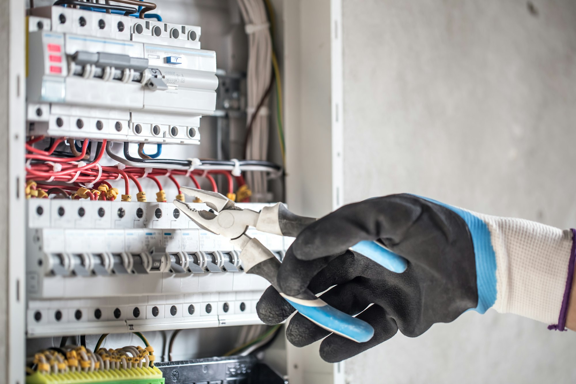 Man, an electrical technician working in a switchboard with fuses.